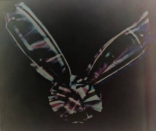 Grainy dark photo with a tartan ribbon in colour against a black background